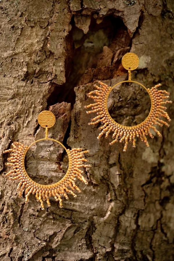 Boucles Apollisia Solaris Valdyria posées sur un fond bois, perles Miyuki dorées et plaqué or.