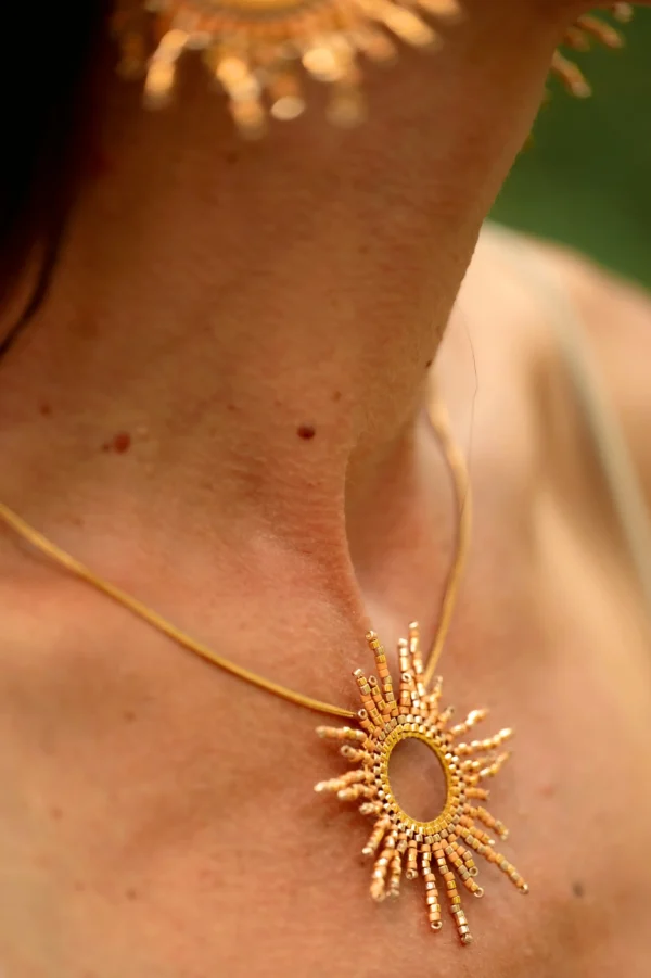 Vue rapprochée du collier sautoir solaire porté en profil, captant la lumière sur la peau.