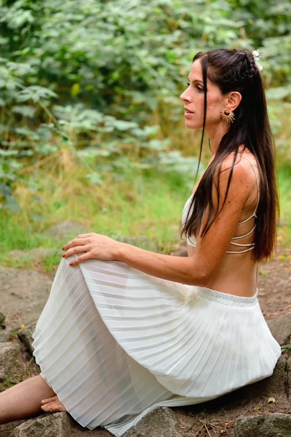 Femme regardant vers la gauche, portant des boucles dorées artisanales au design solaire.