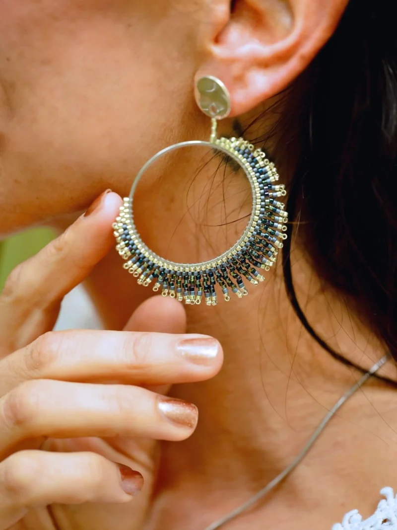 boutique-valdyria-artemesia-lunaris-boucles-oreilles-pendante-gros-plan-oreille-main Boucle d’oreille pendante Artemesia Lunaris Valdyria portée à l’oreille d’une femme, main effleurant le bijou. Bijou artisanal en perles Miyuki argent et bleu, fait main en Alsace, inspiré par la lune.