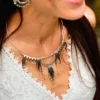 Femme souriante de profil portant le collier Majestueux Artemesia Lunaris Valdyria en perles Miyuki noir, doré et argent. Bijou artisanal fait main.
