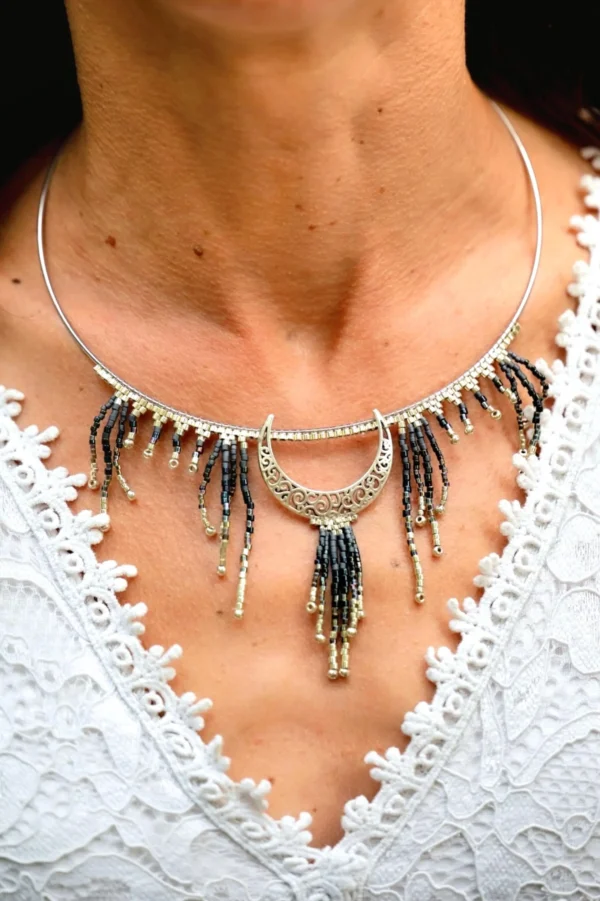 Collier Majestueux Artemesia Lunaris Valdyria porté par une femme, gros plan poitrine, bijou artisanal en perles Miyuki noir, doré et argenté, inspiré de la lune.