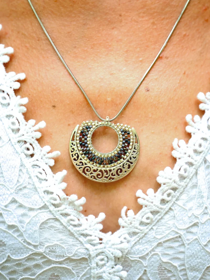 boutique-valdyria-artemesia-lunaris-collier-sautoir-gros-plan-2 Collier Sautoir Artemesia Lunaris Valdyria en métal ciselé et perles Miyuki, porté sur le cou d’une femme en robe blanche.