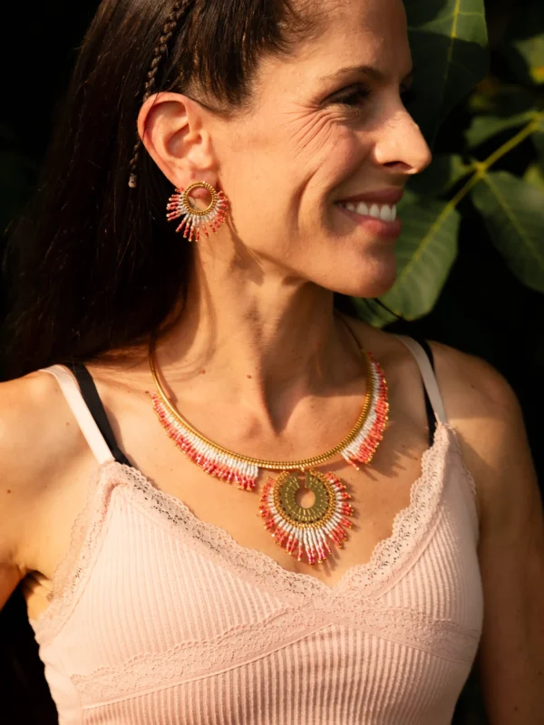 Femme souriante portant le Collier Majestueux Mira Aurora Valdyria, perles Miyuki rose clair et foncé, monture dorée. Bijou artisanal éthique, fait main en Alsace.