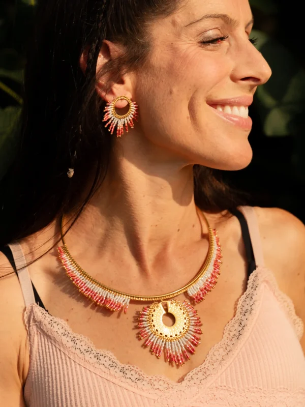 Femme souriante portant le Collier Majestueux Mira Aurora Valdyria et les boucles assorties, perles Miyuki rose clair et foncé. Bijou artisanal français, talisman éthique.
