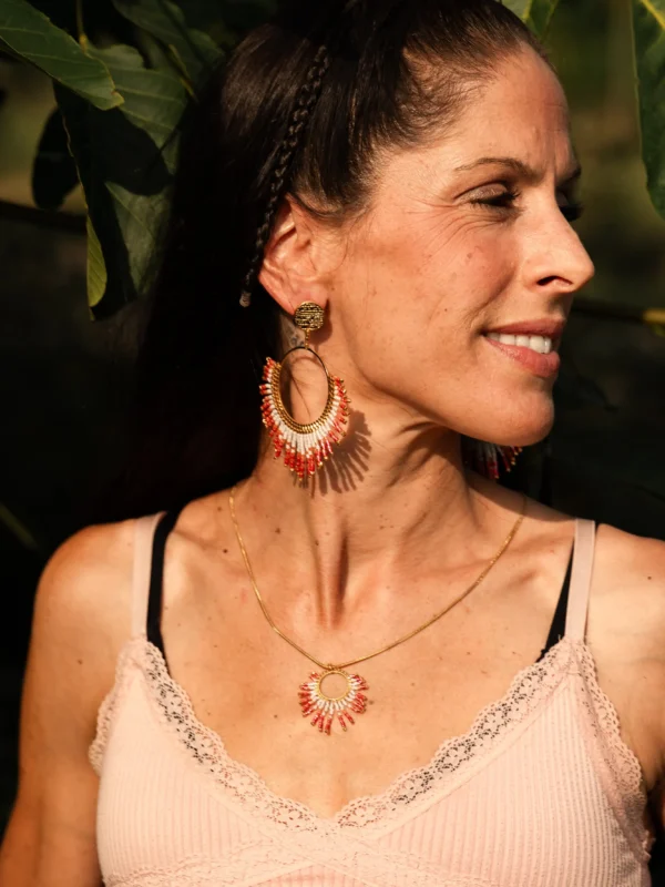 boutique-valdyria-mira-aurora-collier-sautoir-portrait-cheveux-longs Femme souriante aux cheveux longs portant le Collier Sautoir Mira Aurora Valdyria, cercle doré et perles Miyuki rose clair et foncé. Bijou artisanal fait main, éthique.