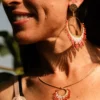 boutique-valdyria-mira-aurora-collier-sautoir-portrait-sourire Femme souriante de profil portant le Collier Sautoir Mira Aurora Valdyria, cercle doré et perles Miyuki rosées. Bijou artisanal alsacien, création durable.