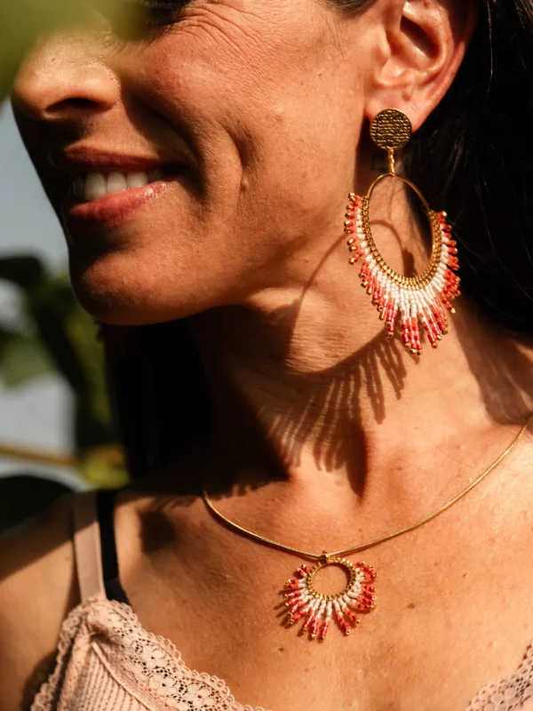 boutique-valdyria-mira-aurora-collier-sautoir-portrait-sourire Femme souriante de profil portant le Collier Sautoir Mira Aurora Valdyria, cercle doré et perles Miyuki rosées. Bijou artisanal alsacien, création durable.