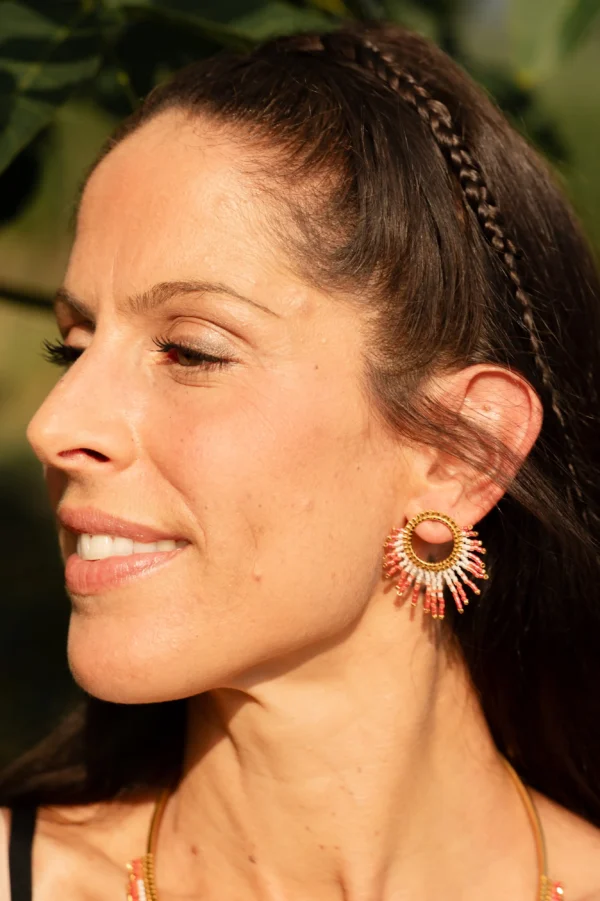 Femme souriante portant une boucle Mira Aurora Valdyria en perles Miyuki rose clair et foncé. Bijou artisanal fait main, écoresponsable et élégant.