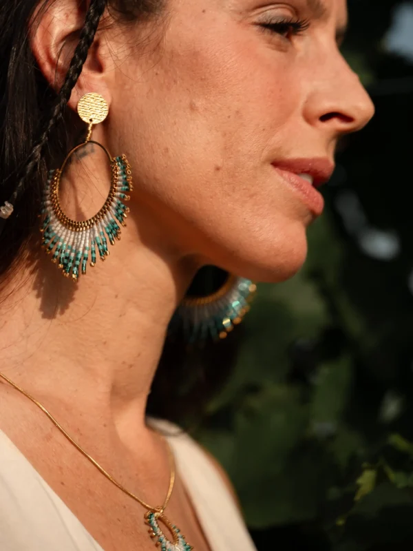 Boucles Mira Calypsa Valdyria portées par une femme de profil, perles Miyuki turquoise et vert d’eau, monture dorée. Bijoux artisanaux éthiques, fabriqués en Alsace.