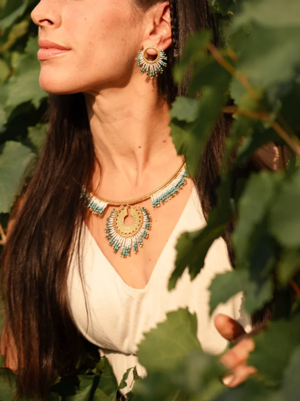 Collier Majestueux Mira Calypsa Valdyria porté au cou, perles Miyuki turquoise et vert d’eau, monture dorée, photographié dans le feuillage. Bijou artisanal made in France, inspiré par la nature.