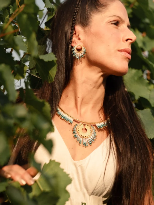 Collier Majestueux Mira Calypsa Valdyria en perles Miyuki turquoise et vert d’eau, monture dorée, porté par une femme de profil. Bijou artisanal alsacien, durable et raffiné.
