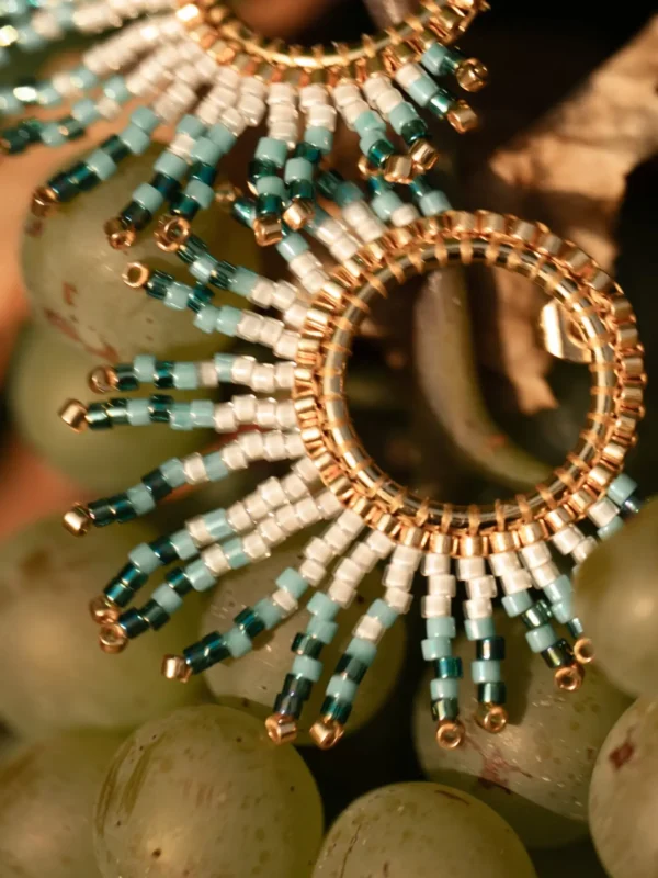 Petites boucles Mira Calypsa Valdyria, tissées de perles Miyuki turquoise et blanches, monture dorée, posées sur des grappes de raisin. Bijoux artisanaux français, poétiques et écoresponsables.