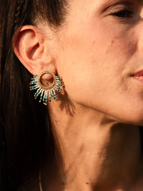 Petite boucle Mira Calypsa Valdyria, tissée de perles Miyuki turquoise et blanches, monture dorée, gros plan portée à l’oreille. Bijou artisanal français, slow creation et poétique.