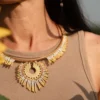 Gros plan du collier Mira Helia en perles Miyuki dorées et blanches, porté au niveau du cou, avec un tournesol en avant-plan. Bijou artisanal français, fait main en Alsace, création durable et solaire.
