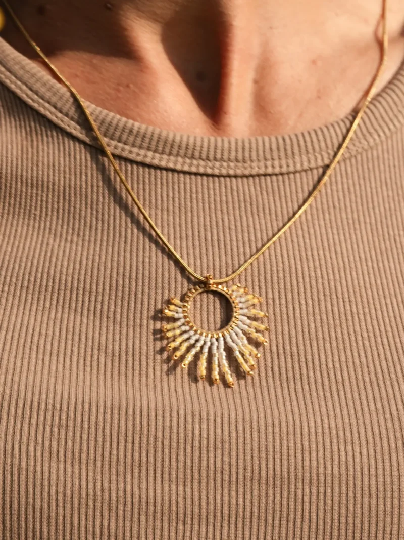 boutique-valdyria-mira-helia-collier-sautoir-gros-plan-lumiere Collier sautoir Mira Helia en perles Miyuki dorées et blanches, porté au niveau du cou. Bijou artisanal français, confectionné à la main en Alsace, création éthique inspirée du soleil.