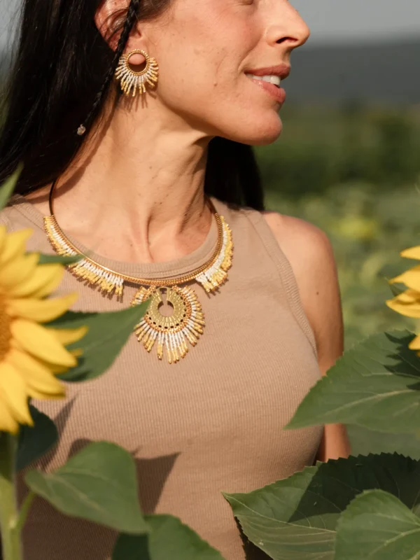 boutique-valdyria-mira-helia-petite-boucle-oreille-parure-sautoir Petite boucle d’oreille Mira Helia en perles Miyuki dorées et blanches, portée avec le collier sautoir Mira Helia. Bijoux artisanaux français, faits main en Alsace, créations écoresponsables et lumineuses.