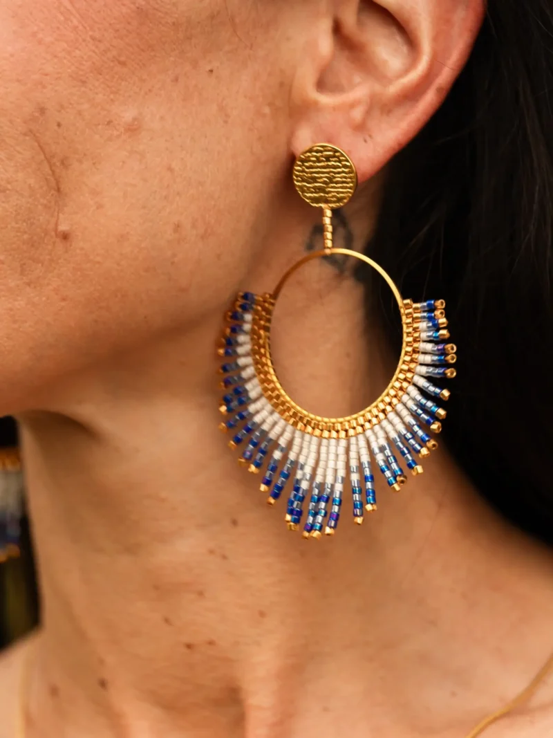 boutique-valdyria-mira-obscura-boucle-oreille-pendante-detail Boucle d’oreille pendante Mira Obscura en perles Miyuki bleues, blanches et dorées, présentée en gros plan. Bijou artisanal français, fait main en Alsace, création durable et poétique.