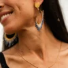 Boucles d’oreilles pendantes Mira Obscura en perles Miyuki bleu nuit et dorées, portées en portrait souriant. Bijoux artisanaux français, faits main en Alsace, créations durables et poétiques.