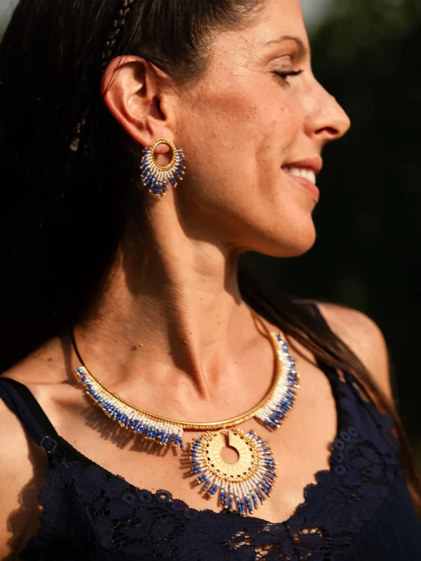 Collier majestueux Mira Obscura en perles Miyuki bleues, dorées et blanches, porté en portrait souriant. Bijou artisanal français, fait main en Alsace, création durable et poétique.