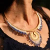 Collier majestueux Mira Obscura en perles Miyuki bleu nuit, blanches et dorées, porté en gros plan avec robe bleu marine. Bijou artisanal français, fait main en Alsace, création durable et inspirée des astres.