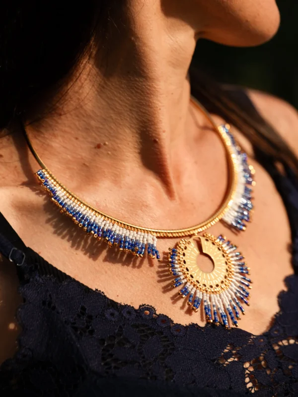 Collier majestueux Mira Obscura en perles Miyuki bleu nuit, blanches et dorées, porté en gros plan avec robe bleu marine. Bijou artisanal français, fait main en Alsace, création durable et inspirée des astres.