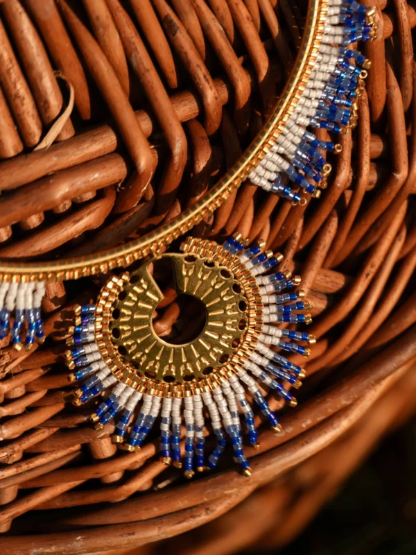 Collier majestueux Mira Obscura en perles Miyuki bleu nuit, dorées et blanches, gros plan posé sur osier. Bijou artisanal français, fait main en Alsace, création durable et poétique.