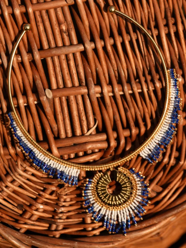 Collier majestueux Mira Obscura en perles Miyuki bleu nuit, dorées et blanches, posé sur osier. Bijou artisanal français, fait main en Alsace, création durable et inspirée des astres.