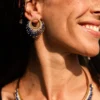 boutique-valdyria-mira-obscura-petites-boucles-oreilles-portrait-souriant Petite boucle d’oreille Mira Obscura en perles Miyuki bleu nuit, blanches et dorées, portée en portrait rapproché. Bijou artisanal français, fait main en Alsace, création durable et cosmique.