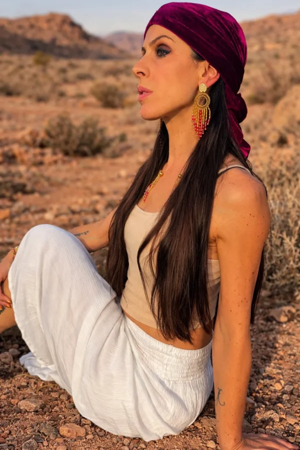 Grandes boucles d’oreilles Amaziga Rubra et ancrage Grandes boucles d’oreilles Amaziga Rubra portées dans un paysage naturel aride inspiré de la terre d’Afrique du Nord