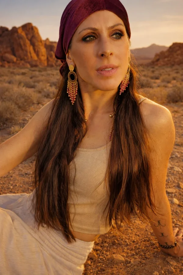 Grandes boucles d’oreilles Amaziga Rubra et présence Grandes boucles d’oreilles Amaziga Rubra portées avec tenue naturelle dans un paysage désertique