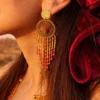 Grandes boucles d’oreilles Amaziga Rubra et détail artisanal Détail grandes boucles d’oreilles Amaziga Rubra avec franges en perles roses et éléments dorés