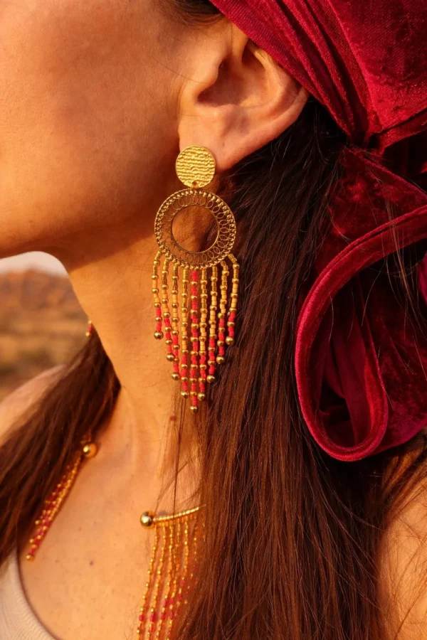 Grandes boucles d’oreilles Amaziga Rubra et détail artisanal Détail grandes boucles d’oreilles Amaziga Rubra avec franges en perles roses et éléments dorés