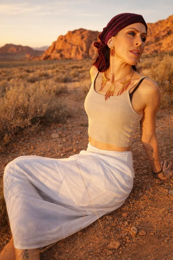 Collier majestueux Amaziga Rubra et corps vivantF Femme assise portant un collier majestueux Amaziga Rubra avec perles roses dans un décor naturel