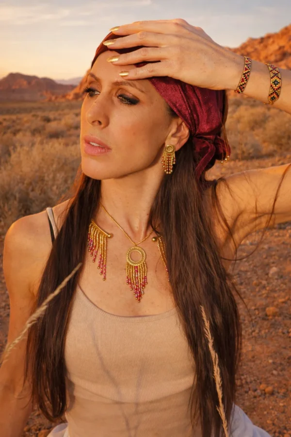 Collier majestueux Amaziga Rubra et vitalité incarnée Collier majestueux Amaziga Rubra porté en gros plan avec perles roses et franges en mouvement