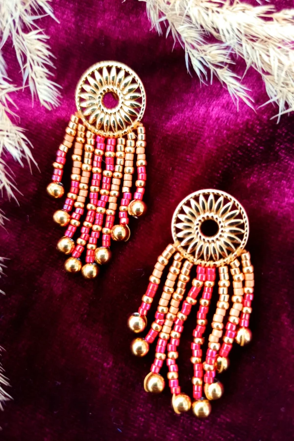 Petites boucles d’oreilles Amaziga Rubra et force vitale Petites boucles d’oreilles Amaziga Rubra posées sur tissu avec perles rouges roses et dorées