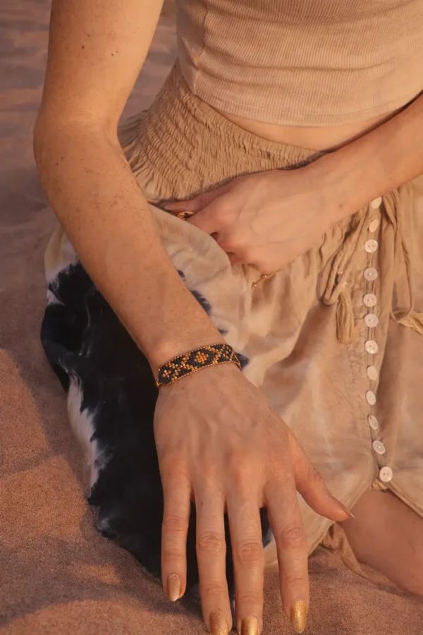 Bracelet bleu irisé Amaziga Sacra porté avec bijoux assortis dans un désert sous lumière naturelle