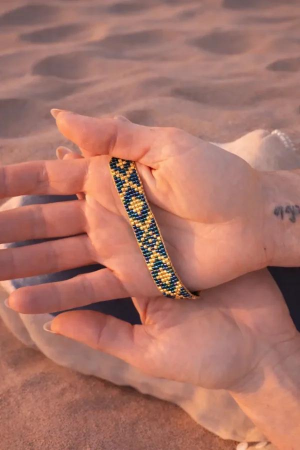 Bracelet bleu irisé Amaziga Sacra porté dans la main avec reflets bleus et détails artisanaux