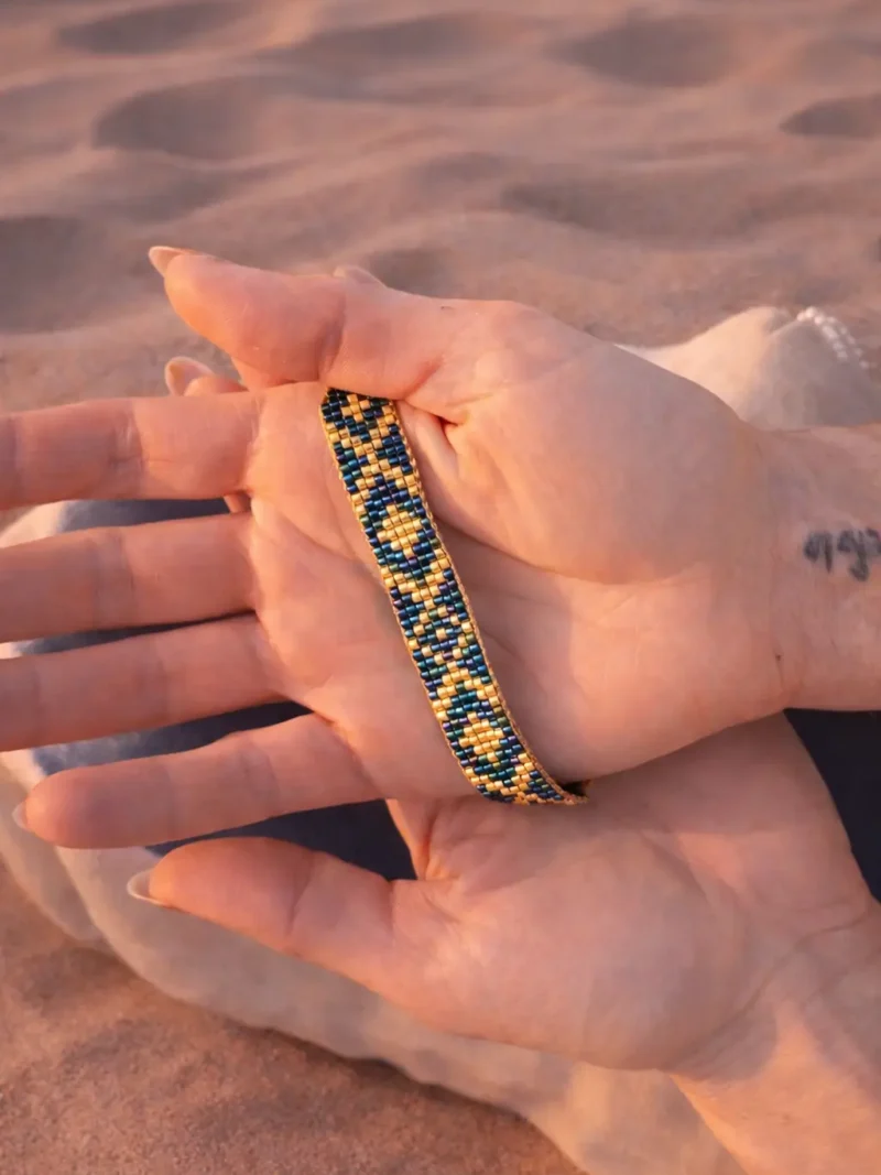 Bracelet bleu irisé Amaziga Sacra porté dans la main avec reflets bleus et détails artisanaux