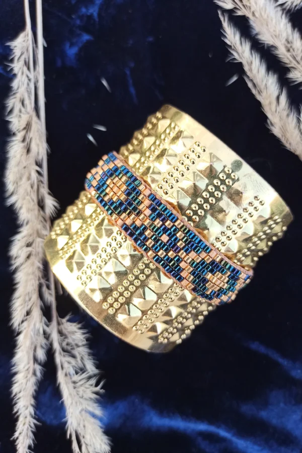 Bracelet bleu irisé Amaziga Sacra posé avec reflets bleus et détails dorés sur fond textile