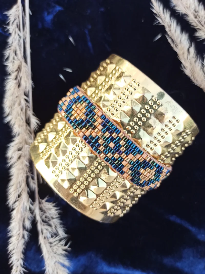 Bracelet bleu irisé Amaziga Sacra posé avec reflets bleus et détails dorés sur fond textile