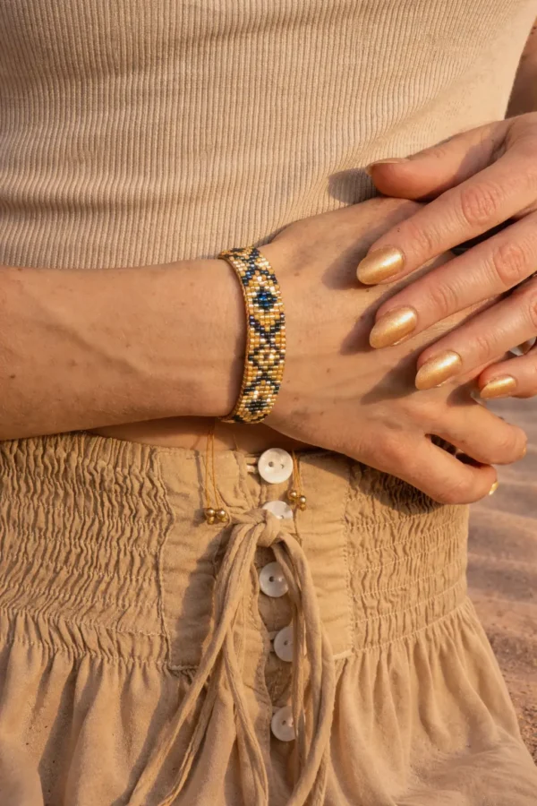 Bracelet bronze Amaziga Sacra porté en gros plan avec perles bleues et détails dorés