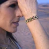 Bracelet bronze Amaziga Sacra porté avec bijoux assortis dans un désert sous lumière naturelle