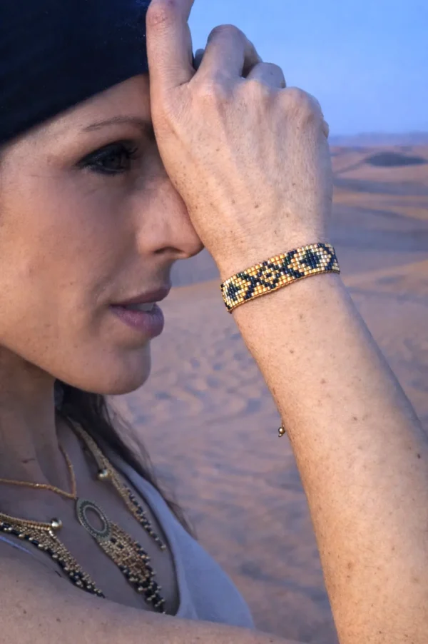Bracelet bronze Amaziga Sacra porté avec bijoux assortis dans un désert sous lumière naturelle