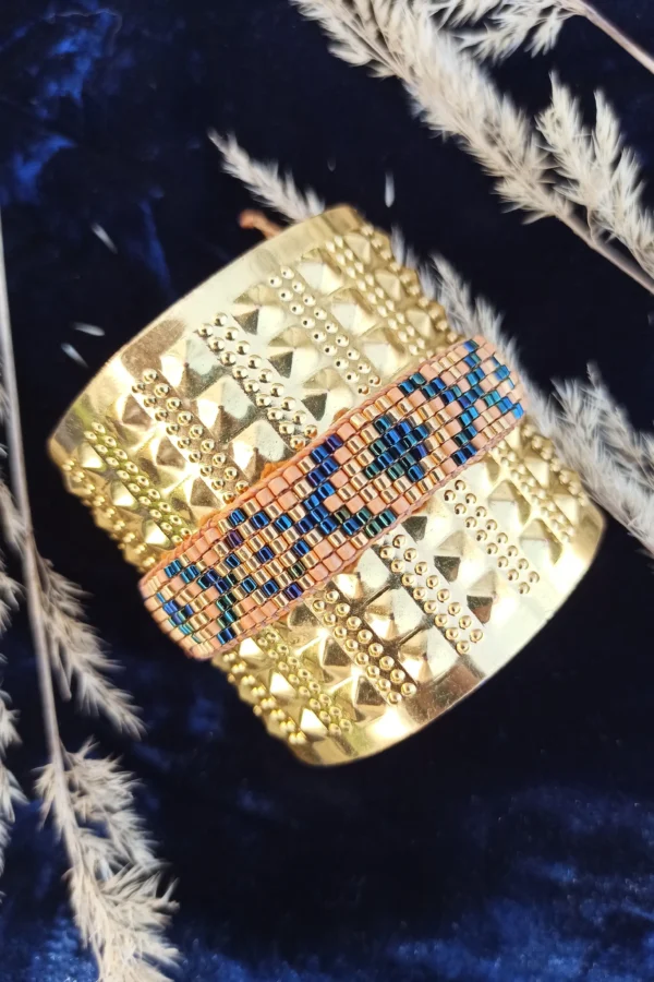 Bracelet bronze Amaziga Sacra posé avec perles bleues et détails dorés sur fond textile