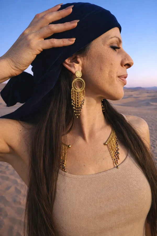 Ces grandes boucles d’oreilles Amaziga Sacra accompagnent la présence et la conscience subtile. Inspirées des rites amazighes, elles évoquent les cycles invisibles et la protection cosmique. Les perles bleues rappellent le ciel et l’énergie subtile. Ce bijou fait main devient un talisman de connexion, entre corps, mémoire et dimension sacrée. Ces grandes boucles d’oreilles Amaziga Sacra accompagnent la présence et la conscience subtile. Inspirées des rites amazighes, elles évoquent les cycles invisibles et la protection cosmique. Les perles bleues rappellent le ciel et l’énergie subtile. Ce bijou fait main devient un talisman de connexion, entre corps, mémoire et dimension sacrée.