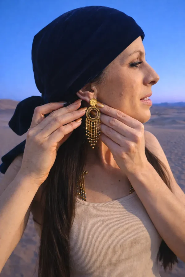 Grandes boucles d’oreilles Amaziga Sacra portées sur la peau avec perles bleues et éléments dorés Grandes boucles d’oreilles Amaziga Sacra portées sur la peau avec perles bleues et éléments dorés