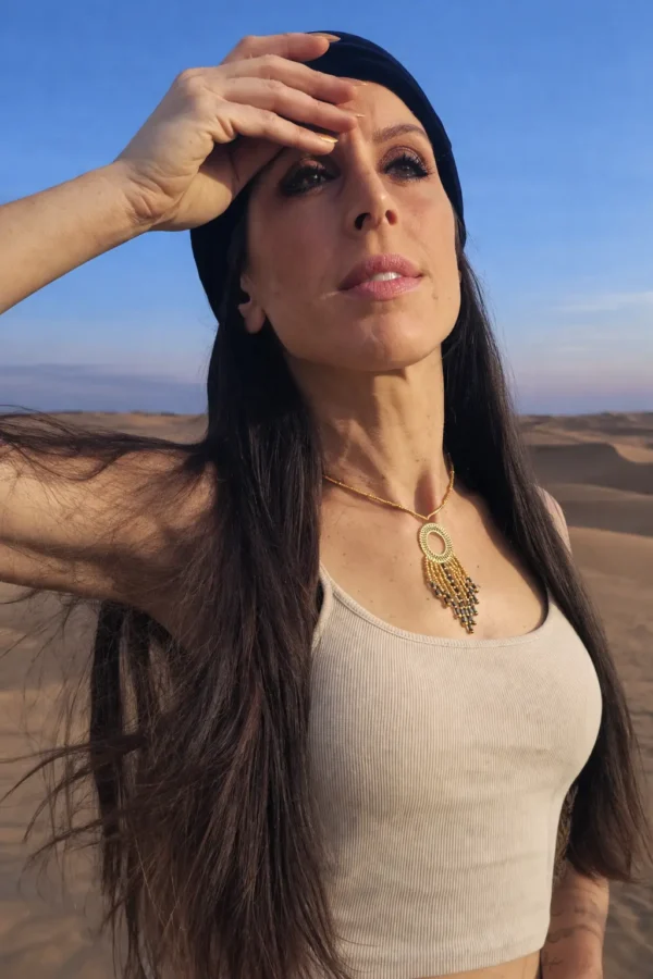 Collier à pendentif Amaziga Sacra et féminité gardienne Collier à pendentif Amaziga Sacra porté par une femme dans un paysage désertique sous ciel clair