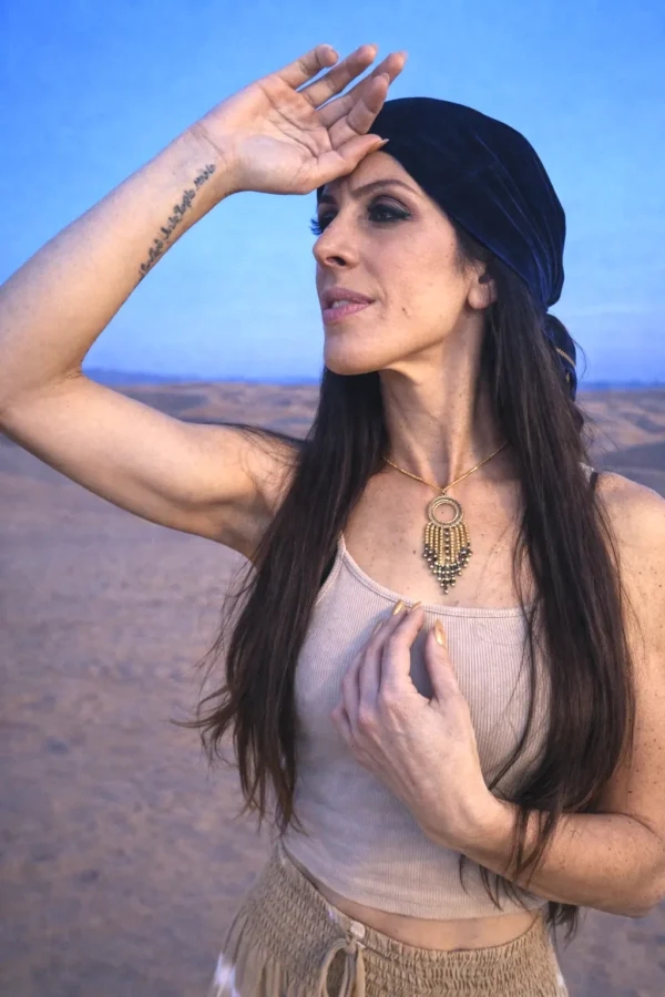 Collier à pendentif Amaziga Sacra porté en gros plan avec pendentif doré et perles bleues Collier à pendentif Amaziga Sacra porté en gros plan avec pendentif doré et perles bleues