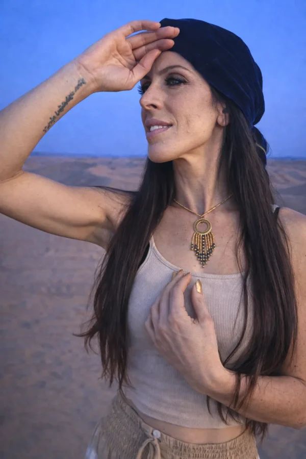 Collier à pendentif Amaziga Sacra et rituel féminin Collier à pendentif Amaziga Sacra porté sur la peau avec perles bleues et pendentif doré